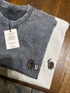 Gray sleeveless shirt with embroidered designs on a wooden surface