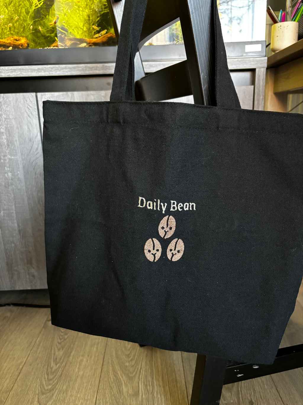 Black chair with 'Daily Bean' logo on a wooden floor