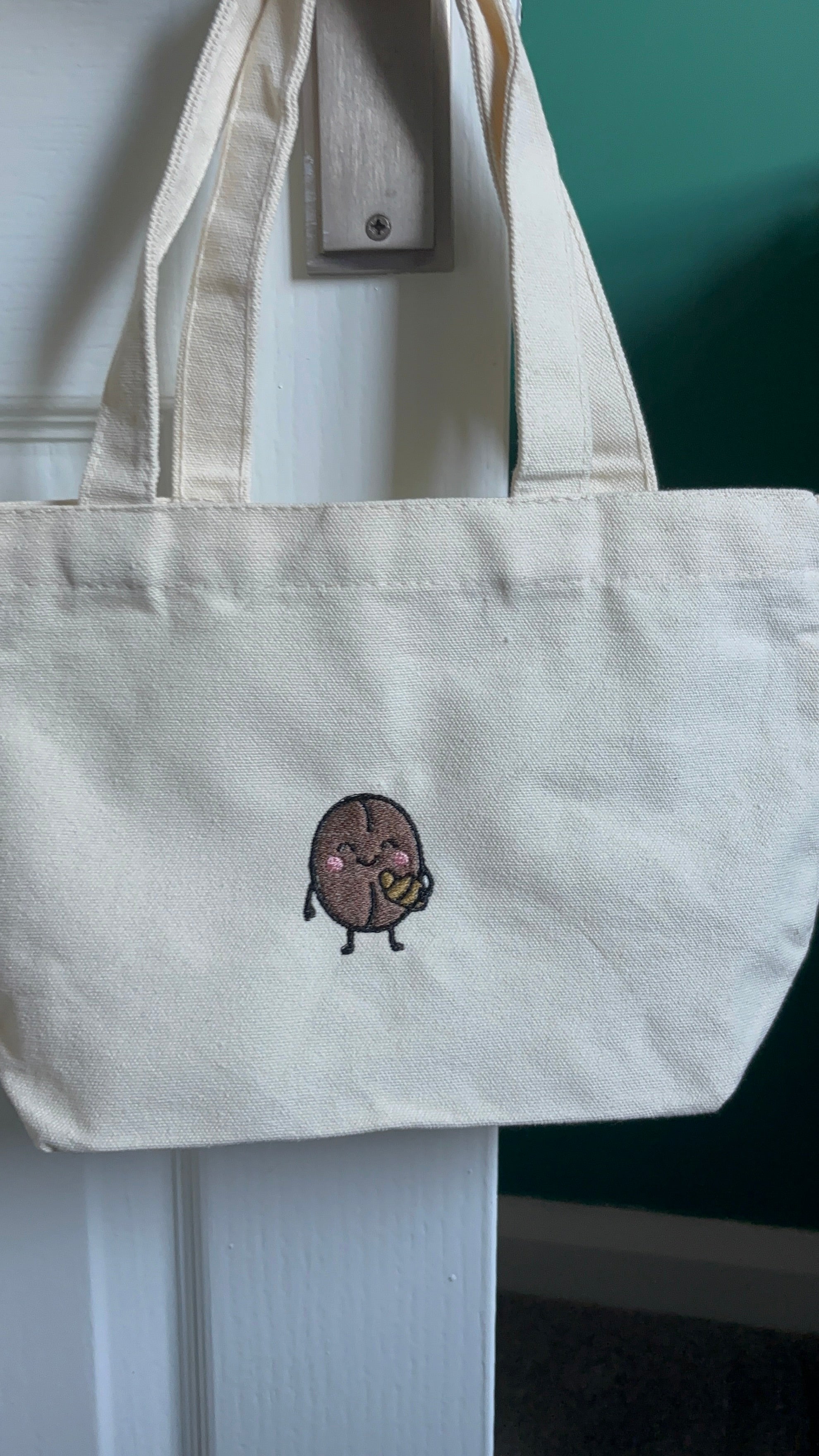 White small tote bag with embodied coffee beans holding croissant 