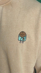 Beige sweatshirt with a small embroidered design on the chest.