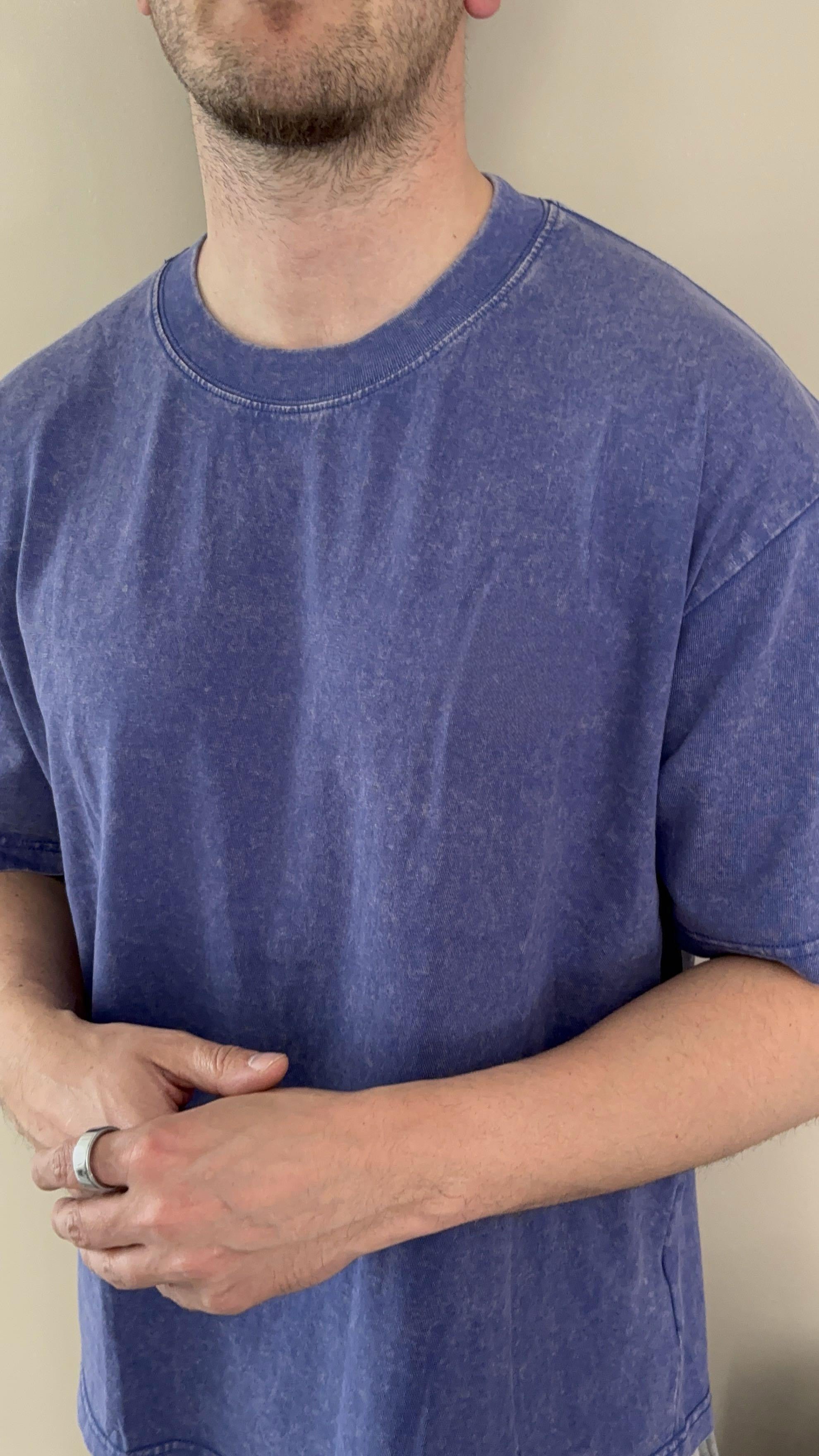 Person wearing a blue t-shirt against a beige background