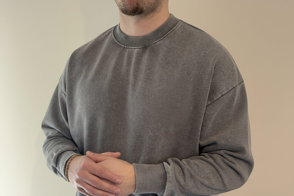 Person wearing a gray sweatshirt with a plain background