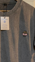 Gray t-shirt with a small logo on a hanger against a white door background