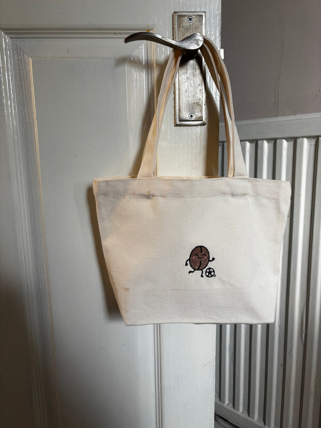 White tote bag with a logo on a metallic surface